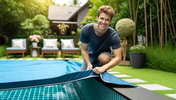 A cheerful person using a navy blue and aqua blue pool cover to conserve water, representing sustainable pool management.